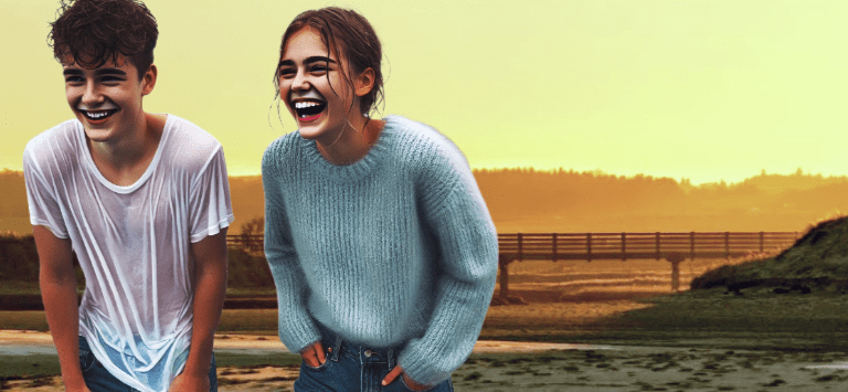 Two young people laughing joyfully by the beach during sunset, with a bridge visible in the background.