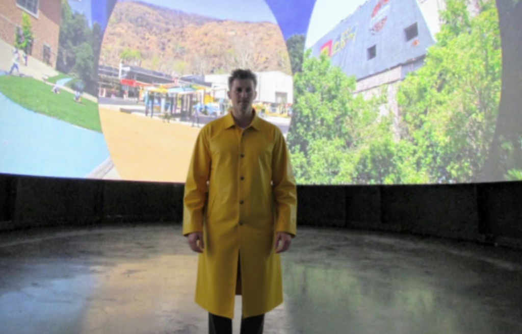 A young man in a yellow rain coat in a studio
